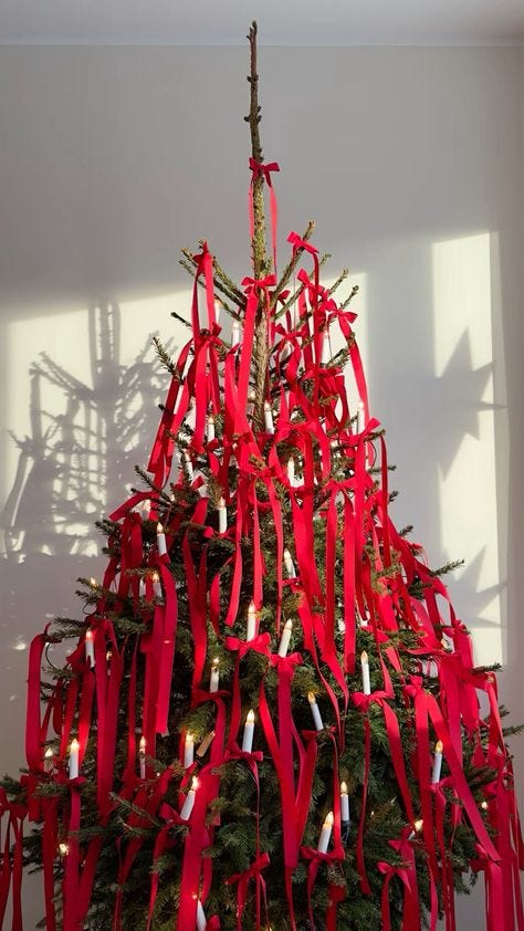 This may contain: a decorated christmas tree with red ribbons and candles in the shape of letters on it