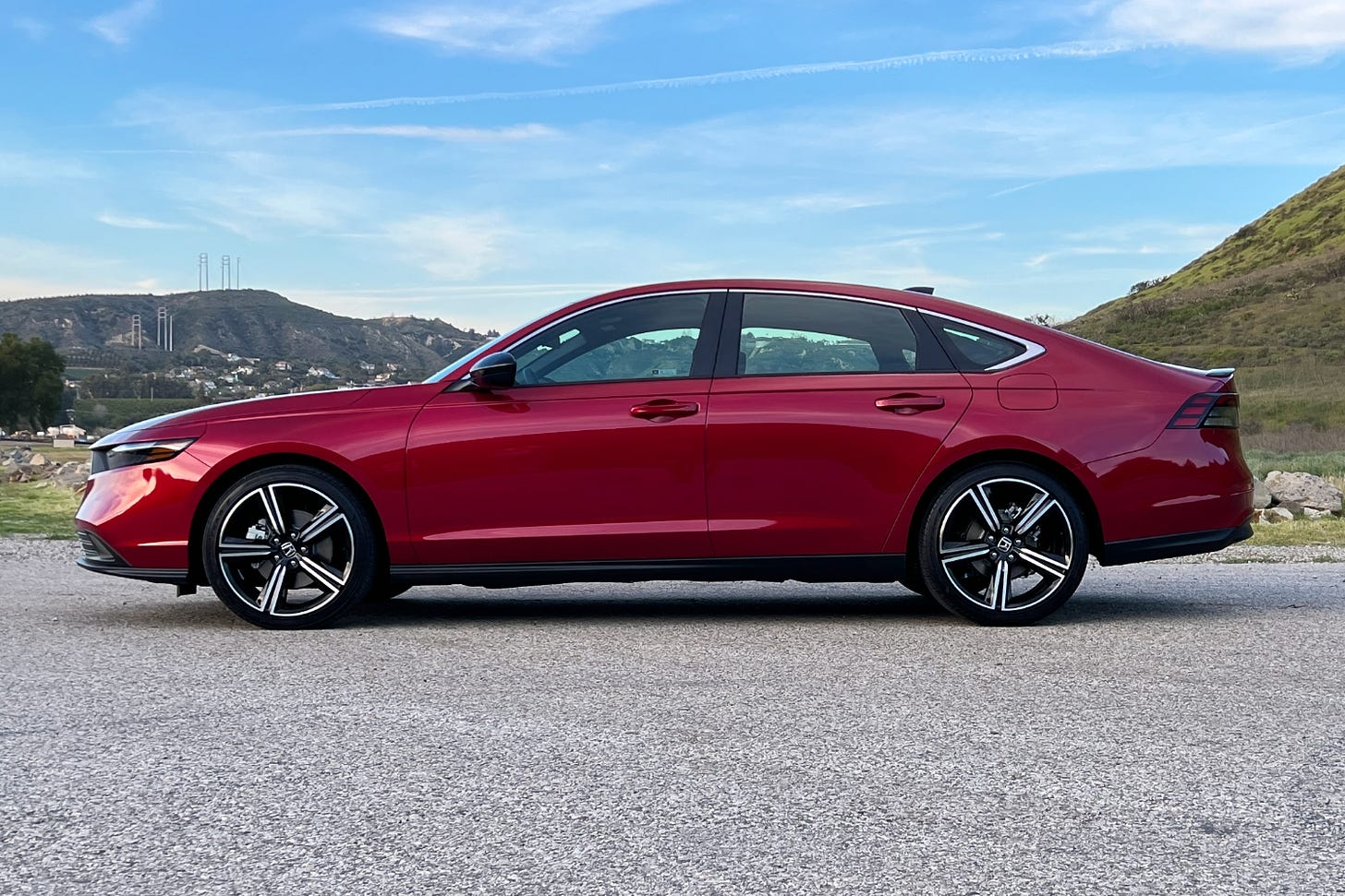 Side view of a red 2023 Honda Accord Sport parked in a lot near mountains.
