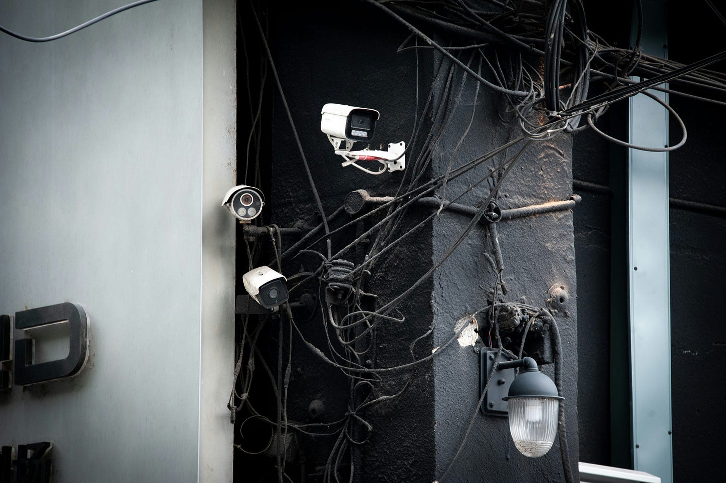 Photo of several surveillance cameras with a tangle of wires in the background.