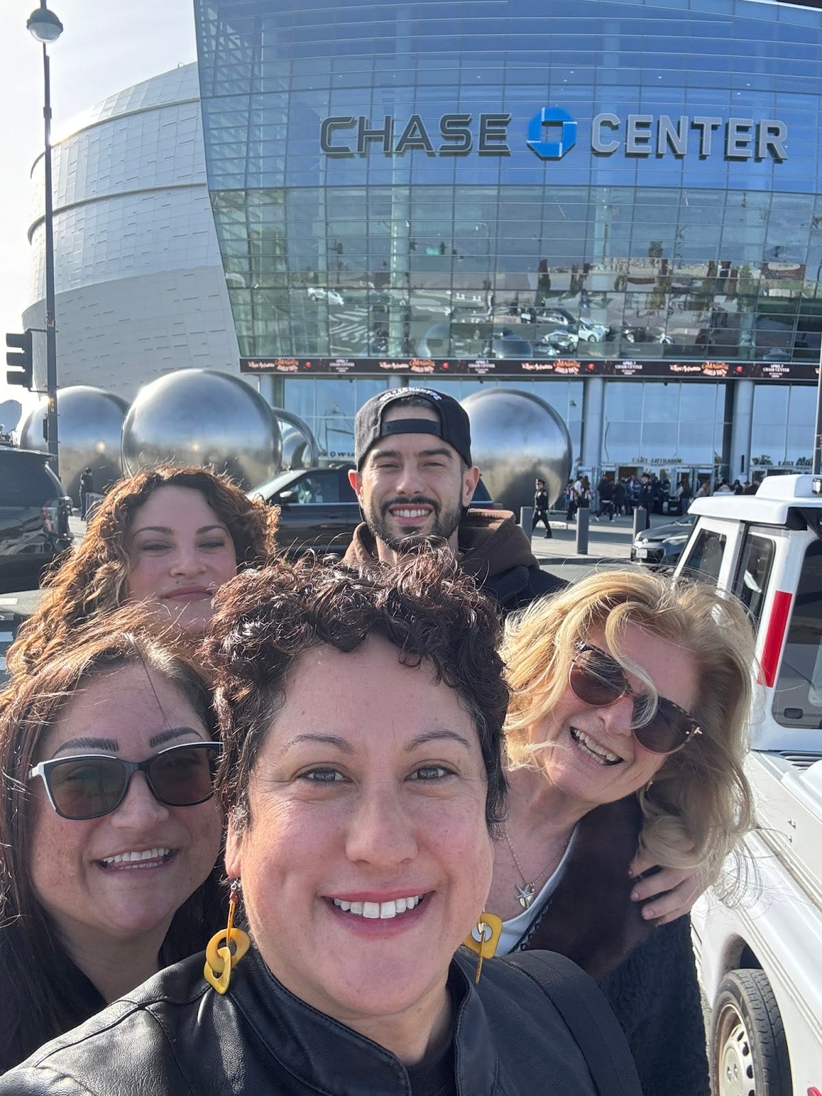 family photo with 4 siblings and 1 mother standing in front of Chase Center