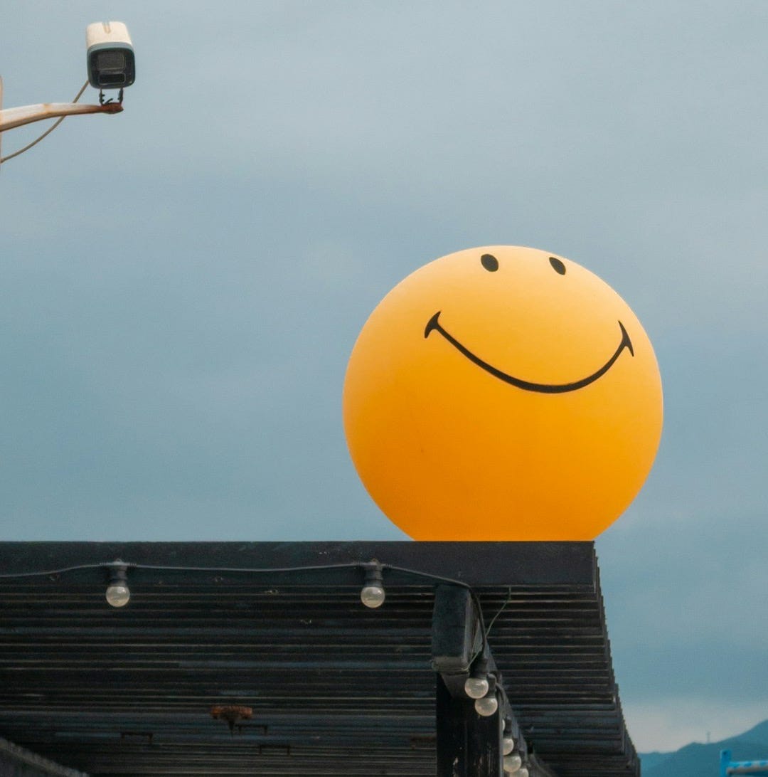 A large yellow smiley face balloon on a rooftop A large yellow smiley face balloon on a rooftop