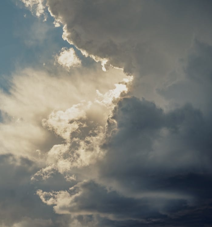 Free A mesmerizing view of sunlight breaking through dark storm clouds in a dramatic sky. Stock Photo