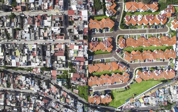 This may contain: an aerial view of houses and roads in the city, with red roofs on them This may contain: an aerial view of houses and roads in the city, with red roofs on them