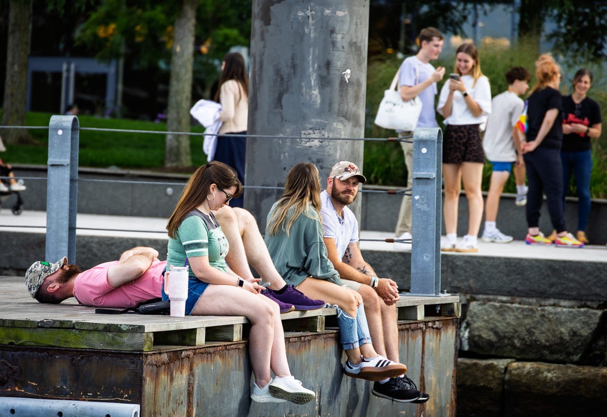 People relaxing on the edge of a pier and one person sleeping