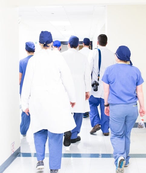 group of doctors walking on hospital hallway group of doctors walking on hospital hallway