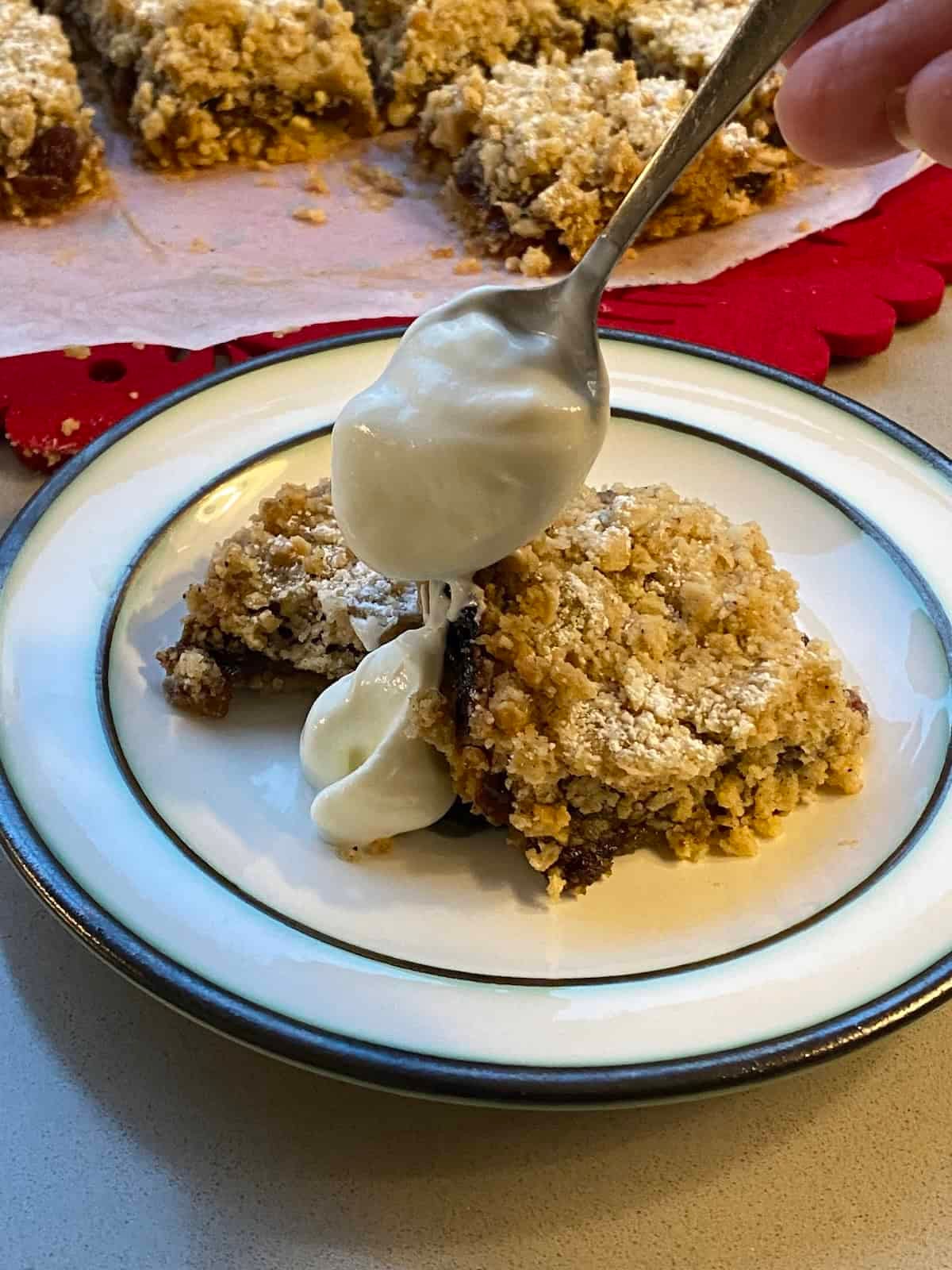 Slices of Mincemeat Crumble Traybake served with plain yogurt.