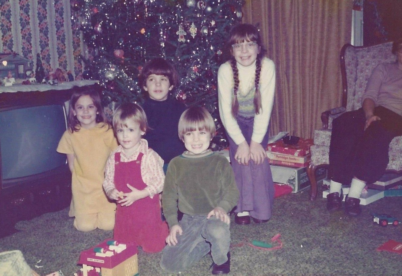 Five young cousins--two girls and three boys--posed together in front of a Christmas tree