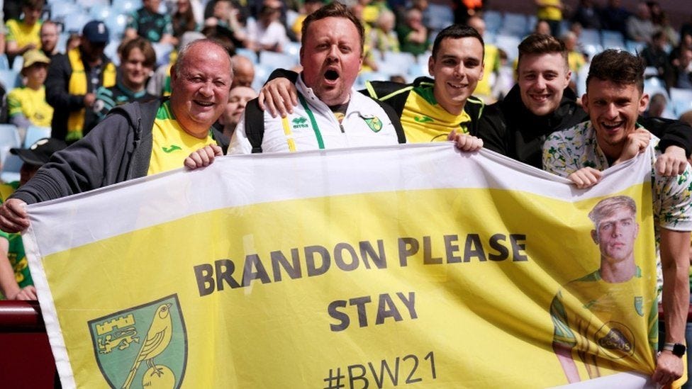 Four Norwich fans hold a professionally made banner, begging Brandon Williams to stay at Norwich City, 2021