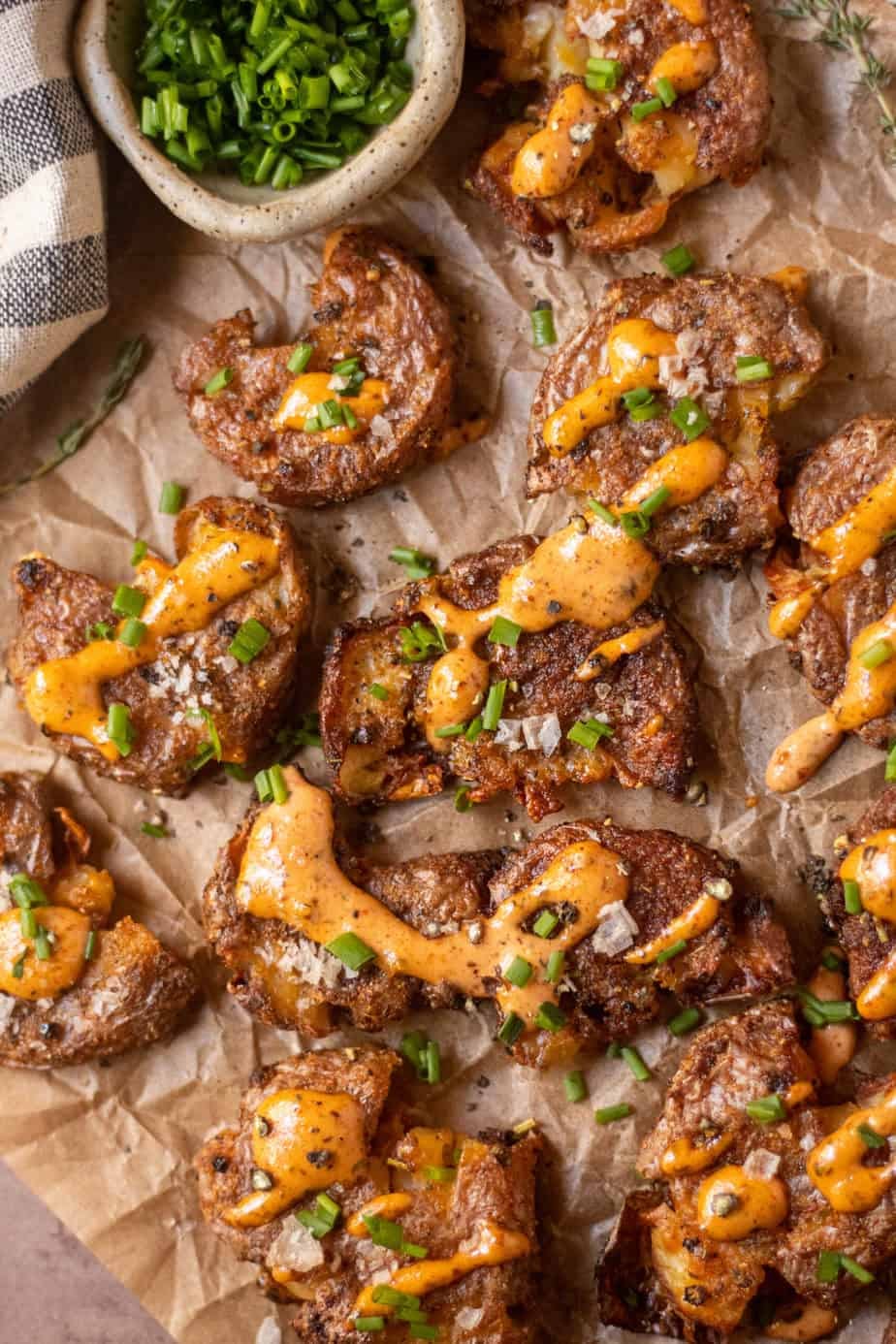 overhead shot of crispy smashed potatoes with creole sauce on parchment paper.