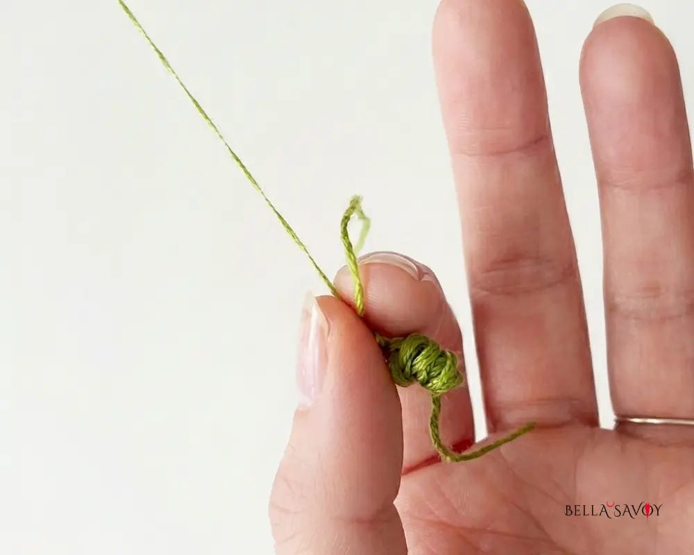 strand of thread being pulled out of skein and curling up below fingers