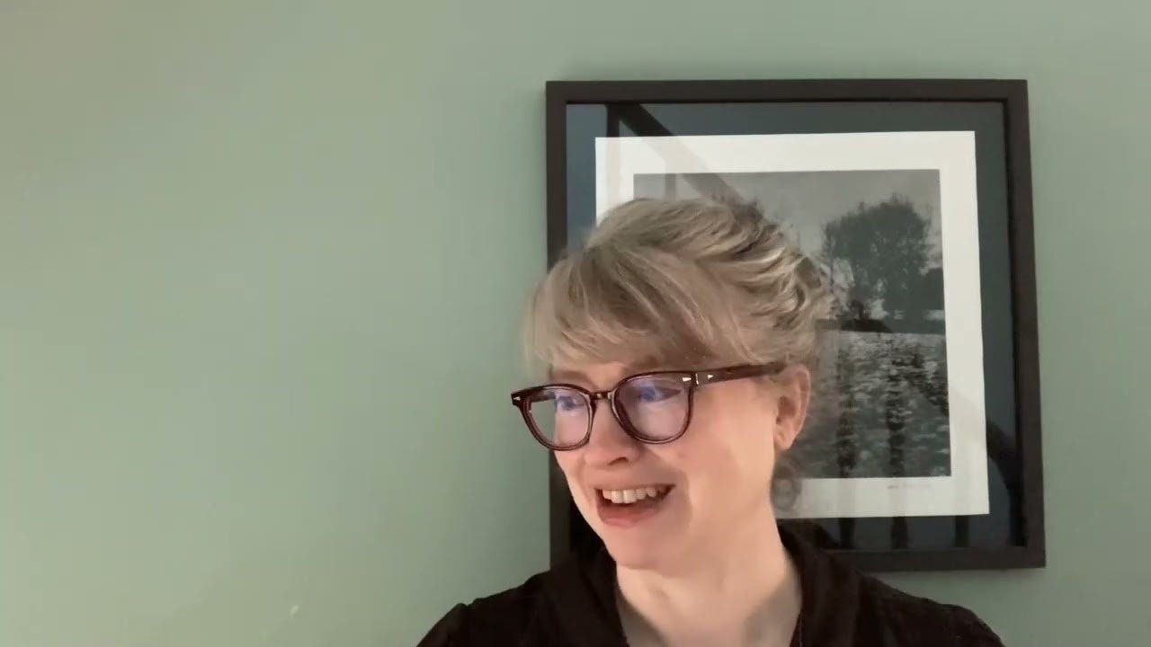 Photo of Natalie Shaw against a green wall in front of a black and white print. Photo of Natalie Shaw against a green wall in front of a black and white print.