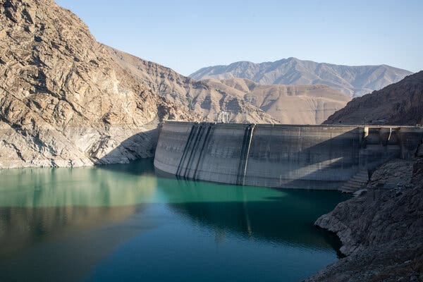 A low reservoir exposes a large part of a dam between arid mountains. A low reservoir exposes a large part of a dam between arid mountains.