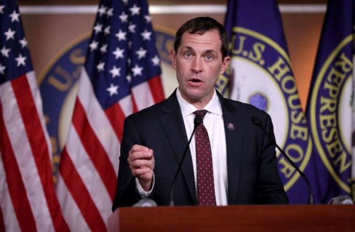 A person standing at a podium with flags behind him

Description automatically generated