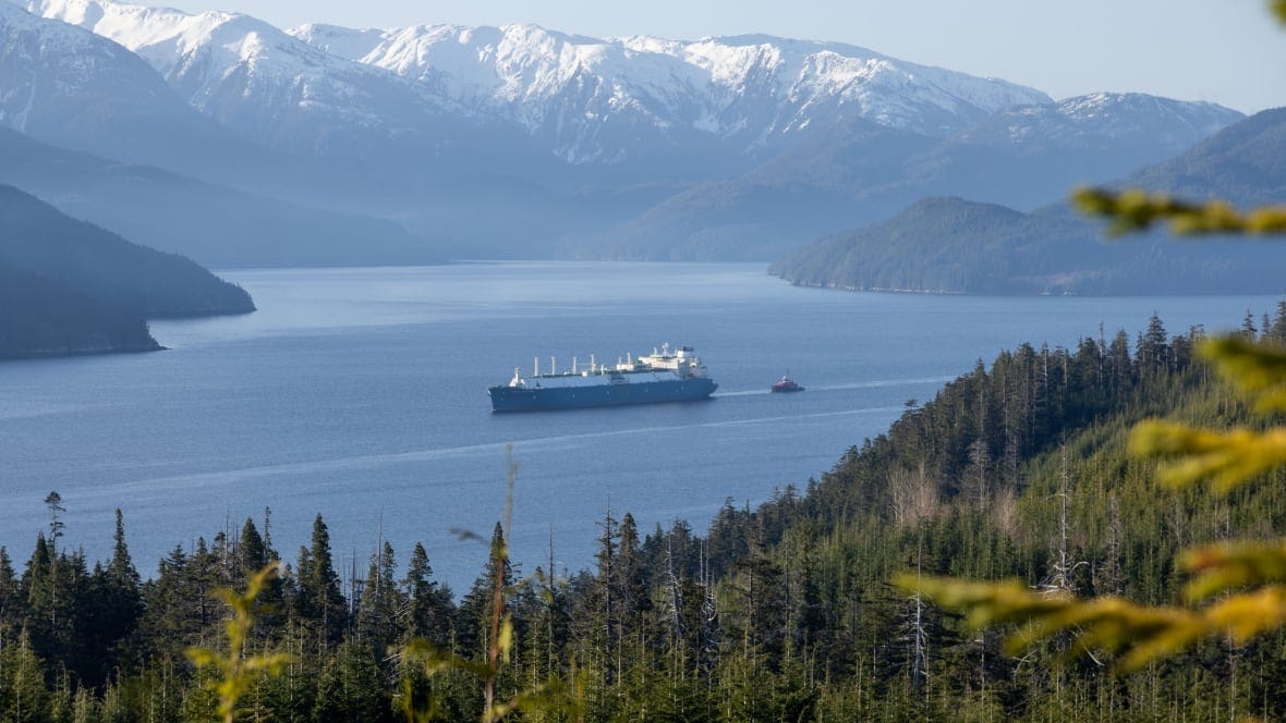 A distant shot of a freighter pulled by a tugboat.