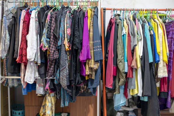 Lots of old, colorful clothes hung chaotically on the iron railings near the closets. Lots of old, colorful clothes hung chaotically on the iron railings near the closets and baskets in the corners of an old concrete house in rural Thailand. overflowing retail racks stock pictures, royalty-free photos & images