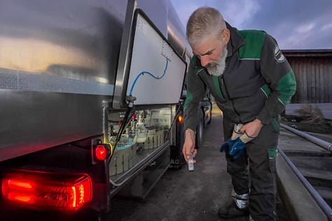 **Alt-Text für die Bilderreihe:** 1. Ein Milchsammelwagen steht vor einer Molkerei im Naturpark Diemtigtal. Es ist eine kalte, klare Winternacht, und der Lastwagen ist bereit für die Milchabholung. 2. Der Fahrer des Milchsammelwagens entnimmt eine Probe aus der gesammelten Milch. Die Szene zeigt ihn in Arbeitskleidung, umgeben von der technischen Ausstattung des Tankwagens. 3. Der Milchsammelwagen fährt über eine verschneite Straße, im Hintergrund erhebt sich der imposante, schneebedeckte Gipfel des Niesen. Die Landschaft ist malerisch und klar. 4. Der Lastwagen steht vor einem traditionellen Bauernhof, während der Fahrer den Milchschlauch in den Milchtank des Hofes anschließt. Die Morgensonne beleuchtet das Haus und die winterliche Umgebung. 5. Im Milchraum eines Bauernhofs entleert der Fahrer die gesammelte Milch in einen großen Edelstahltank. Das Bild zeigt die saubere und organisierte Arbeitsumgebung. 6. Der Fahrer, in warmer Arbeitskleidung, lächelt in die Kamera. Im Hintergrund steht der Milchsammelwagen, umgeben von der frostigen Landschaft des Diemtigtals.