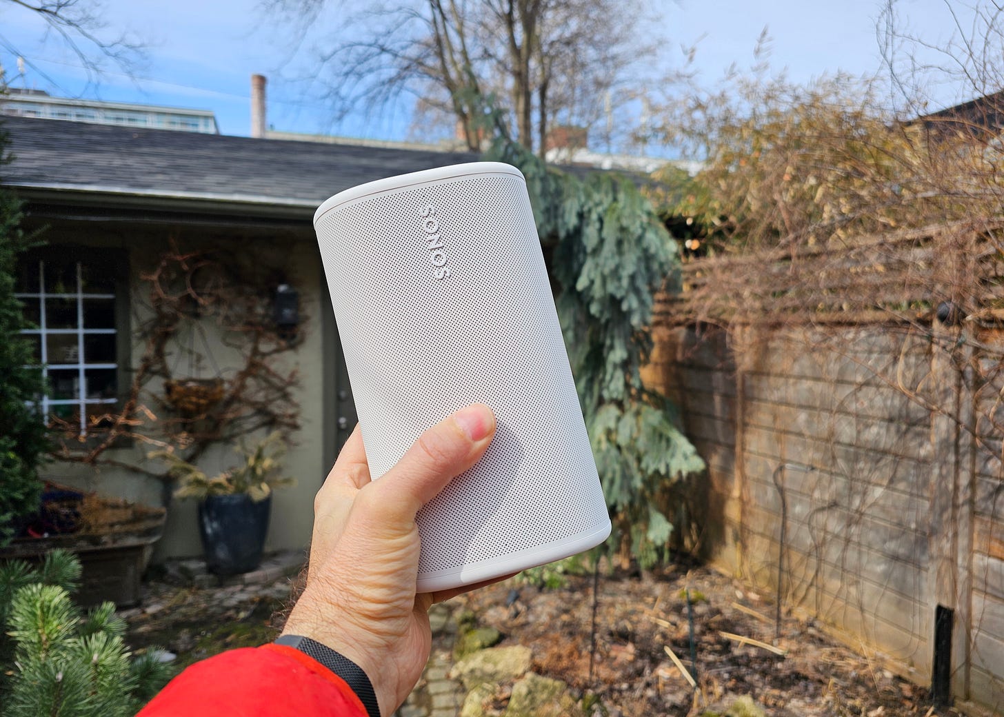 Someone holding a white Sonos Play aloft in one hand. Someone holding a white Sonos Play aloft in one hand.