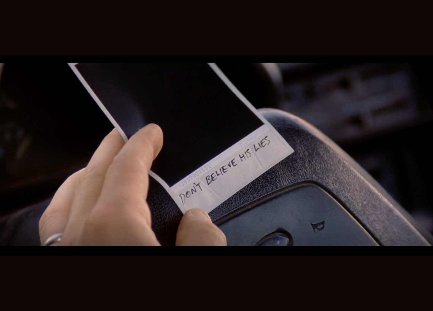 Picture from the movie Memento with the polaroid picture underneath which it is written: "Don't believe his lies."