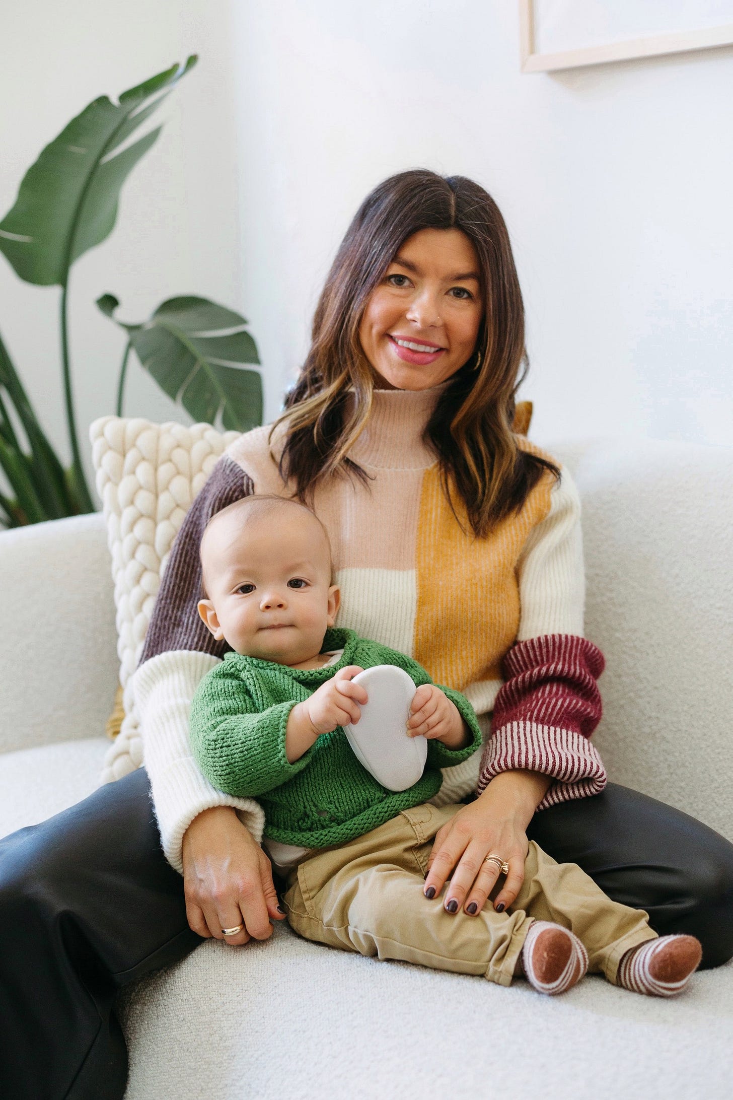 Sera Michael with her first child, sitting on a white couch
