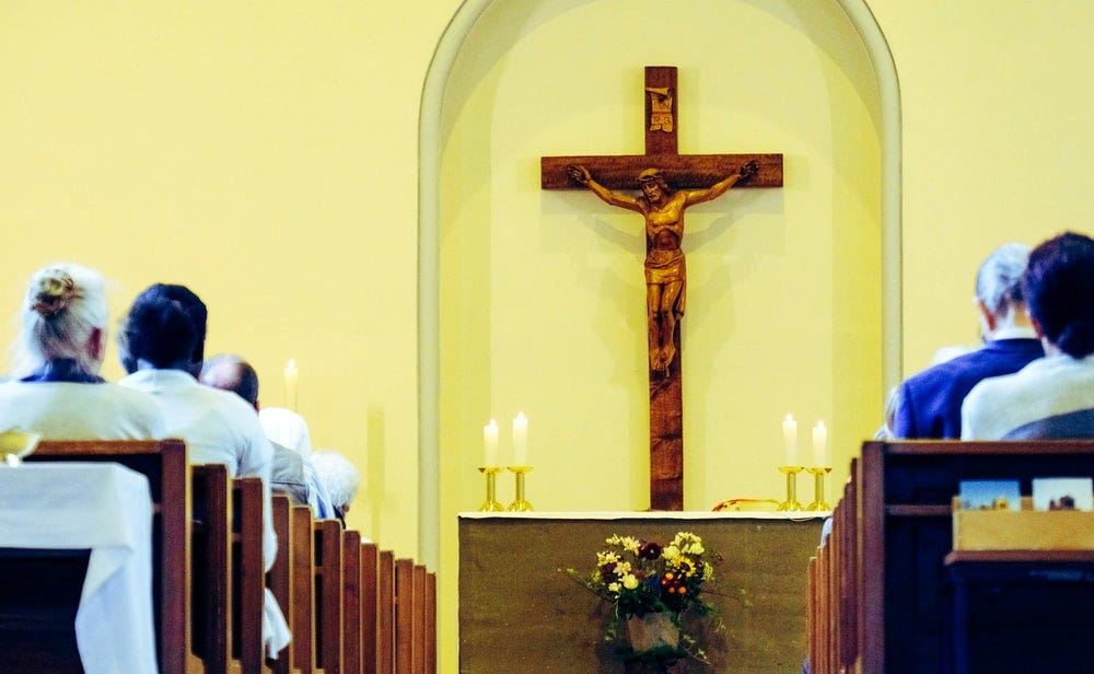 people sitting on bench in front of altar with crucifix