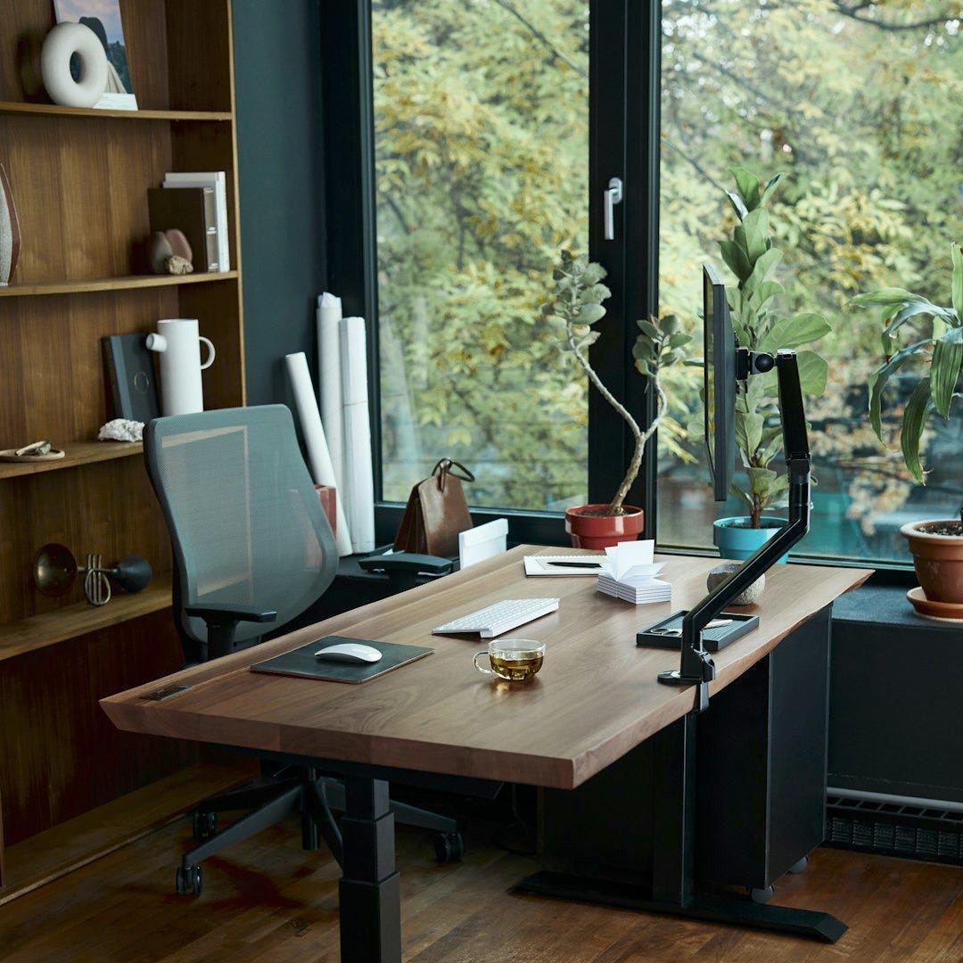 a desk with a laptop on it in front of a window a desk with a laptop on it in front of a window