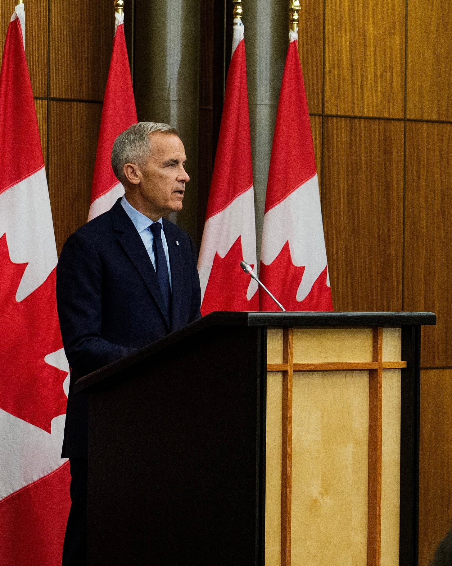 Photo of Prime Minister Carney at a podium delivering an update on Canada-U.S. trade.