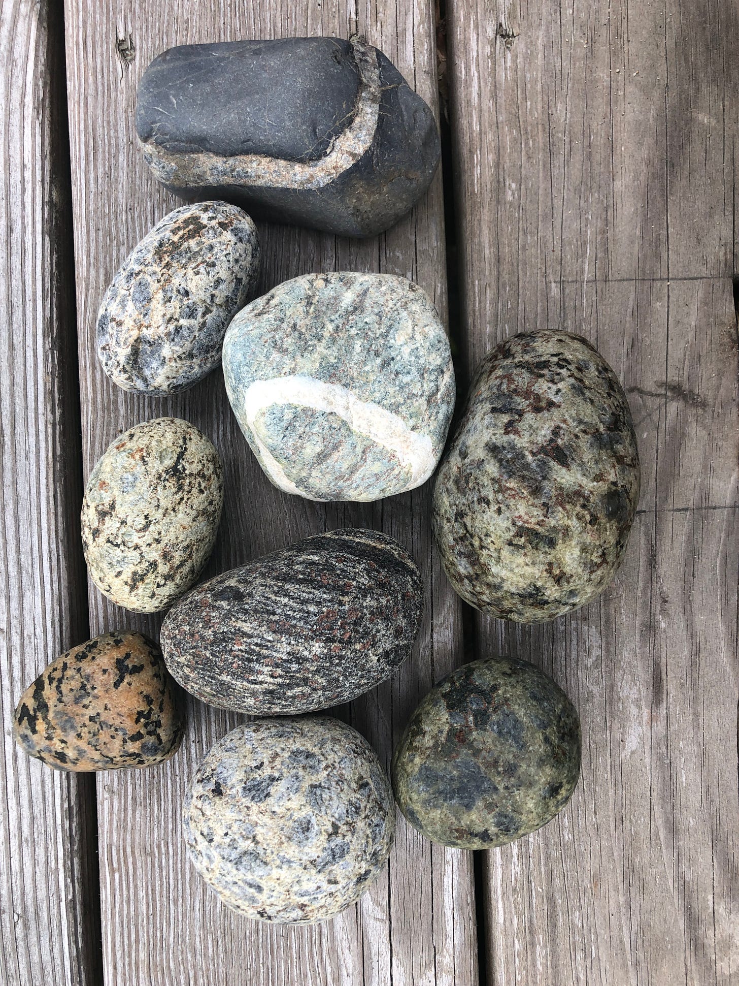 Seven stones on a worn picnic table, many of them with circles through them, most likely granite. Seven stones on a worn picnic table, many of them with circles through them, most likely granite.