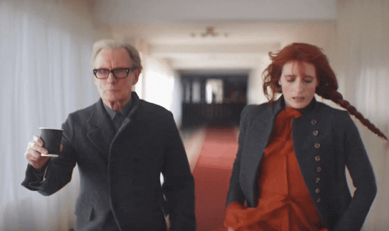 Gif com Florence e Bill Nighy correndo assoberbados por um corredor