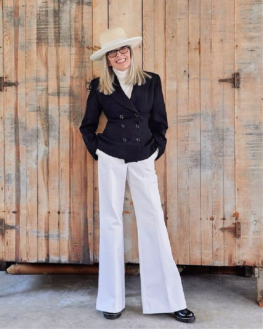 Diane Keaton wearing a wide brim hat, a navy double breasted blazer, and white wide legged pants. Diane Keaton wearing a wide brim hat, a navy double breasted blazer, and white wide legged pants.
