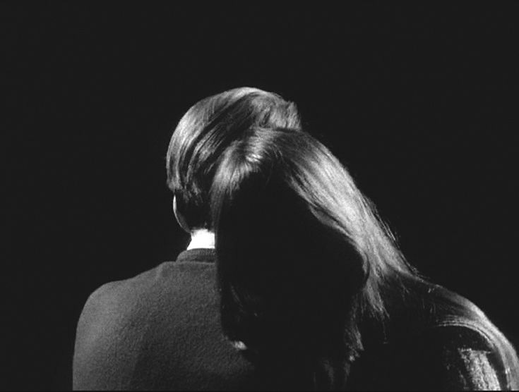 This may contain: black and white photograph of a woman with her back to the camera, looking down