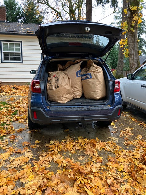Subara hatch open with bags of leaves, food drive and leave drop-off sign, tractor lift