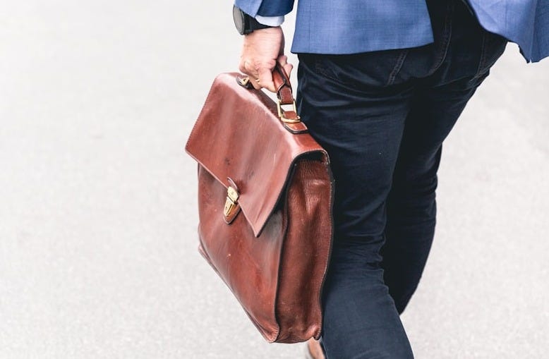 person walking holding brown leather bag person walking holding brown leather bag