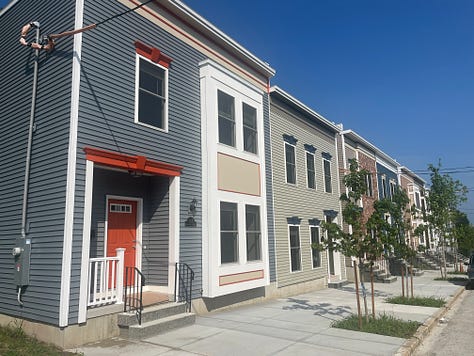 Exterior photos of new townhouses from the street and from the backyard. Several interior photos of a first floor with an open layout.