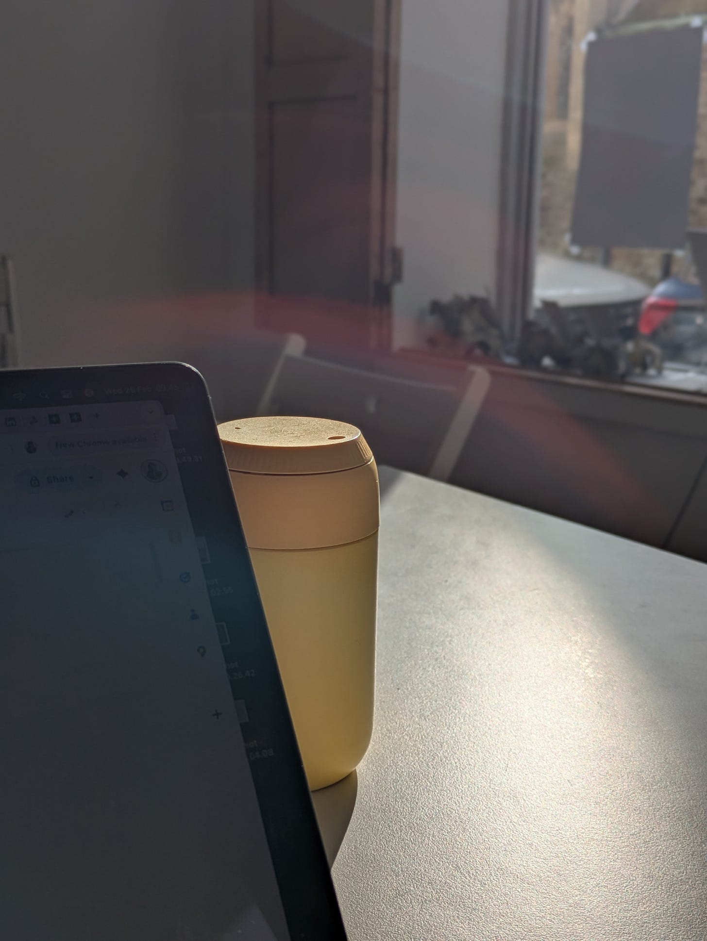Grace's large yellow Chilly's keep cup on a desk at the writing workshop, sun streaming in through the window and reflecting on the sliver of laptop screen visible on the left side of the cup. Grace's large yellow Chilly's keep cup on a desk at the writing workshop, sun streaming in through the window and reflecting on the sliver of laptop screen visible on the left side of the cup.