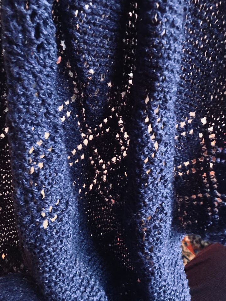 A garter stitch lace shawl and a cone of purple wool