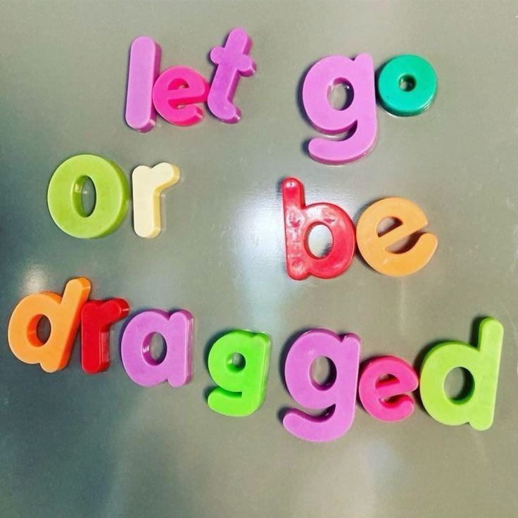 A collection of multicolor fridge magnet letters that reads "let go or be dragged"