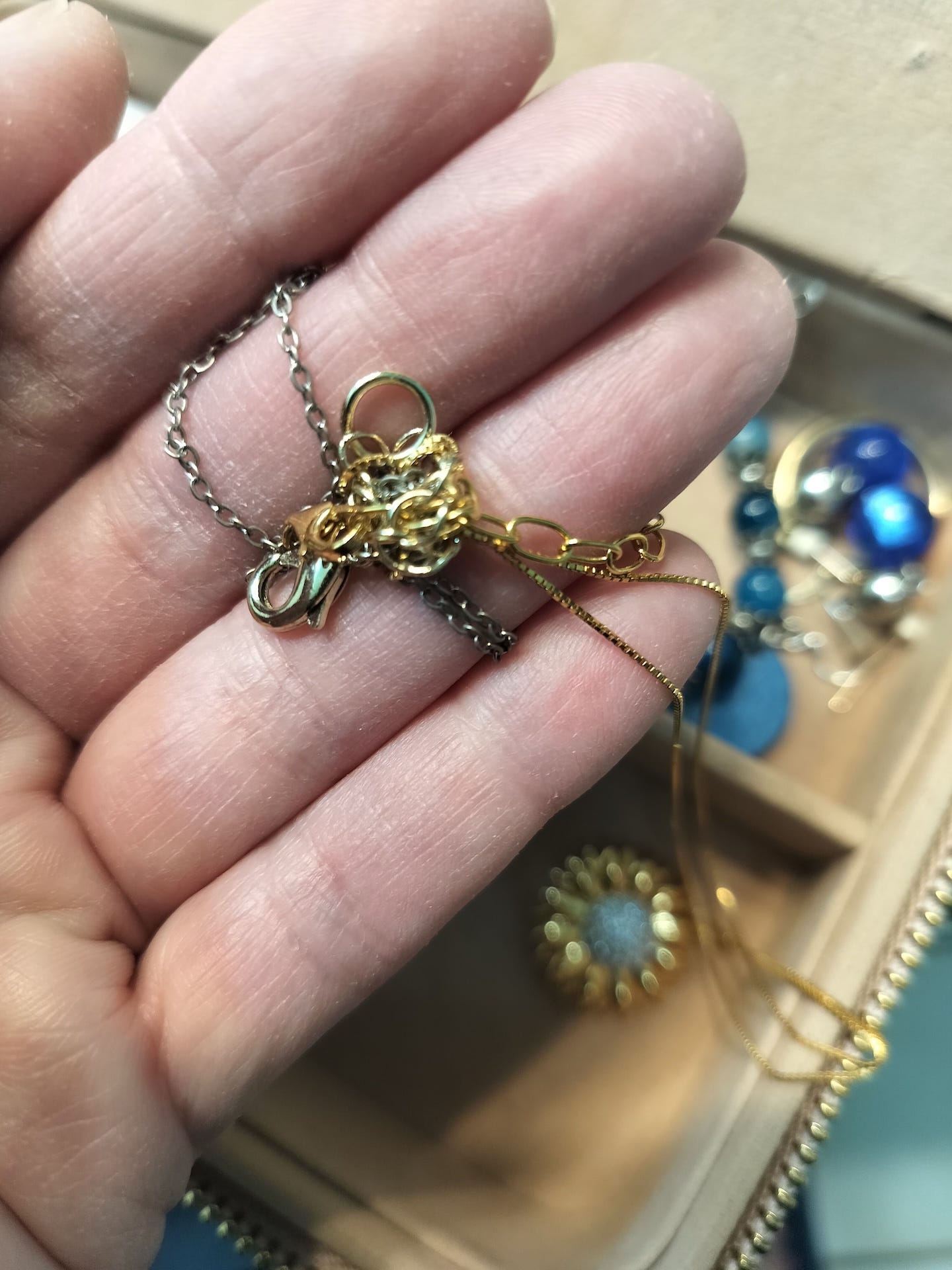 A hand holding a tangled assortment of necklaces.