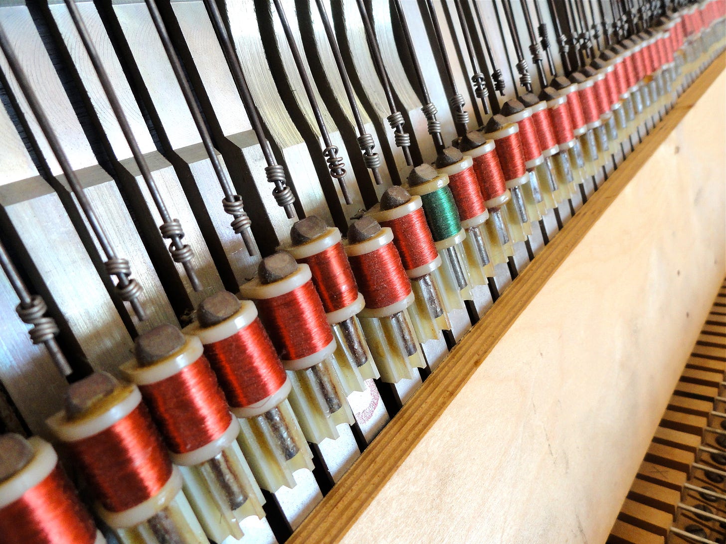 A close-up image of a piano with red and green spools, revealing the distinctive 4" red wire pickups housed in the prototype Fender Rhodes piano. A close-up image of a piano with red and green spools, revealing the distinctive 4" red wire pickups housed in the prototype Fender Rhodes piano.