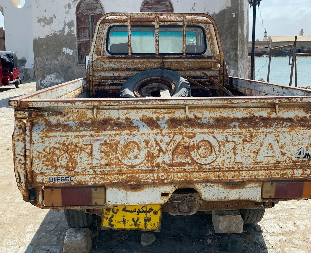 an old rusted truck parked in front of a building