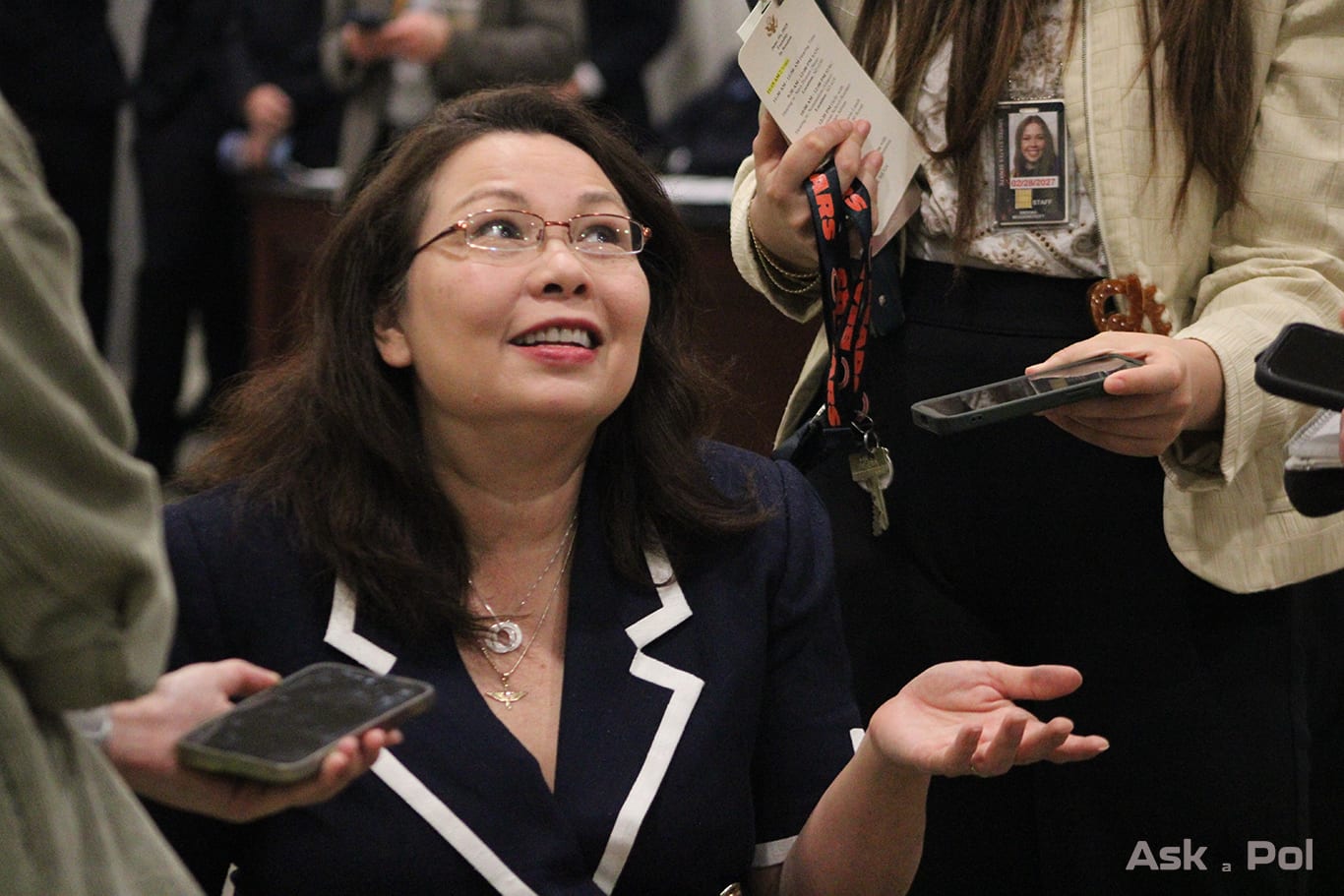 A lady with glasses in a wheelchair has one palm pointed upwards as she looks to reporters abover her like she's asking questions rhetorically Photo Logan Johnson for © www.askapolpolitics.com A lady with glasses in a wheelchair has one palm pointed upwards as she looks to reporters abover her like she's asking questions rhetorically Photo Logan Johnson for © www.askapolpolitics.com