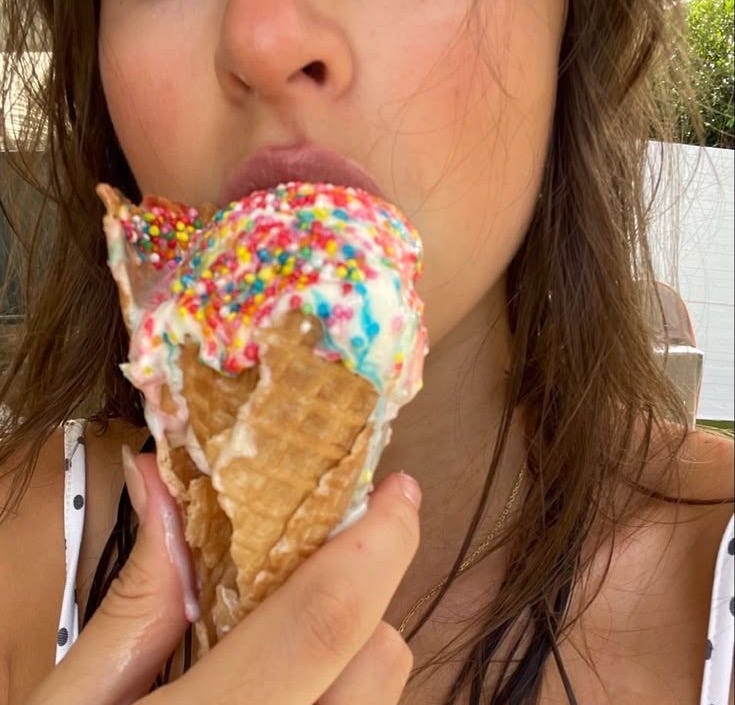 This may contain: a woman eating an ice cream cone with sprinkles This may contain: a woman eating an ice cream cone with sprinkles