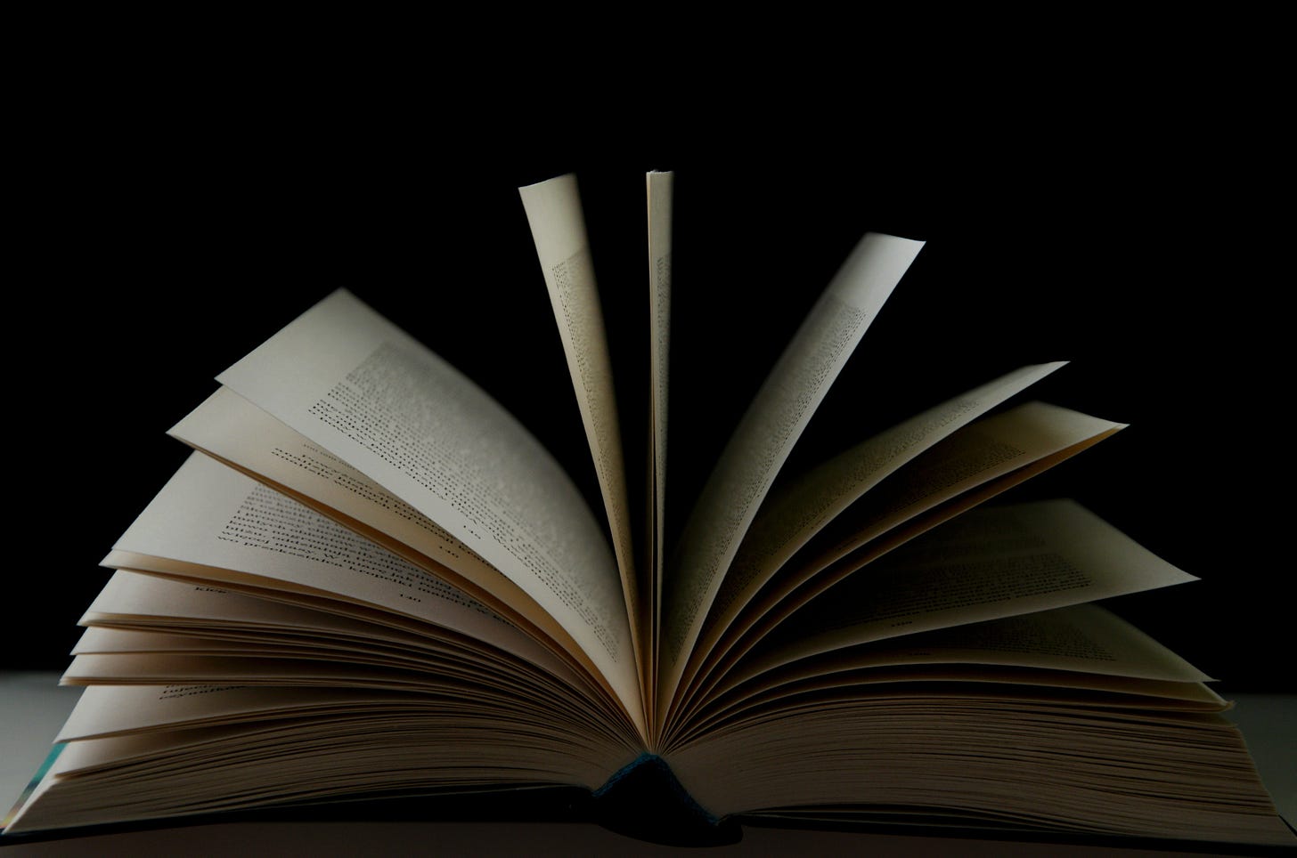 A book sits on a table with its pages fanned open. A book sits on a table with its pages fanned open.