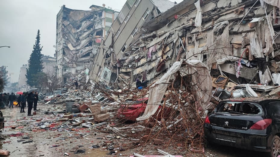 People stand in front of collapsed buildings following an earthquake in Kahramanmaras, Turkey February 6, 2023. Ihlas News Agency (IHA) via REUTERS ATTENTION EDITORS - THIS PICTURE WAS PROVIDED BY A THIRD PARTY. NO RESALES. NO ARCHIVES. TURKEY OUT. NO COMMERCIAL OR EDITORIAL SALES IN TURKEY.