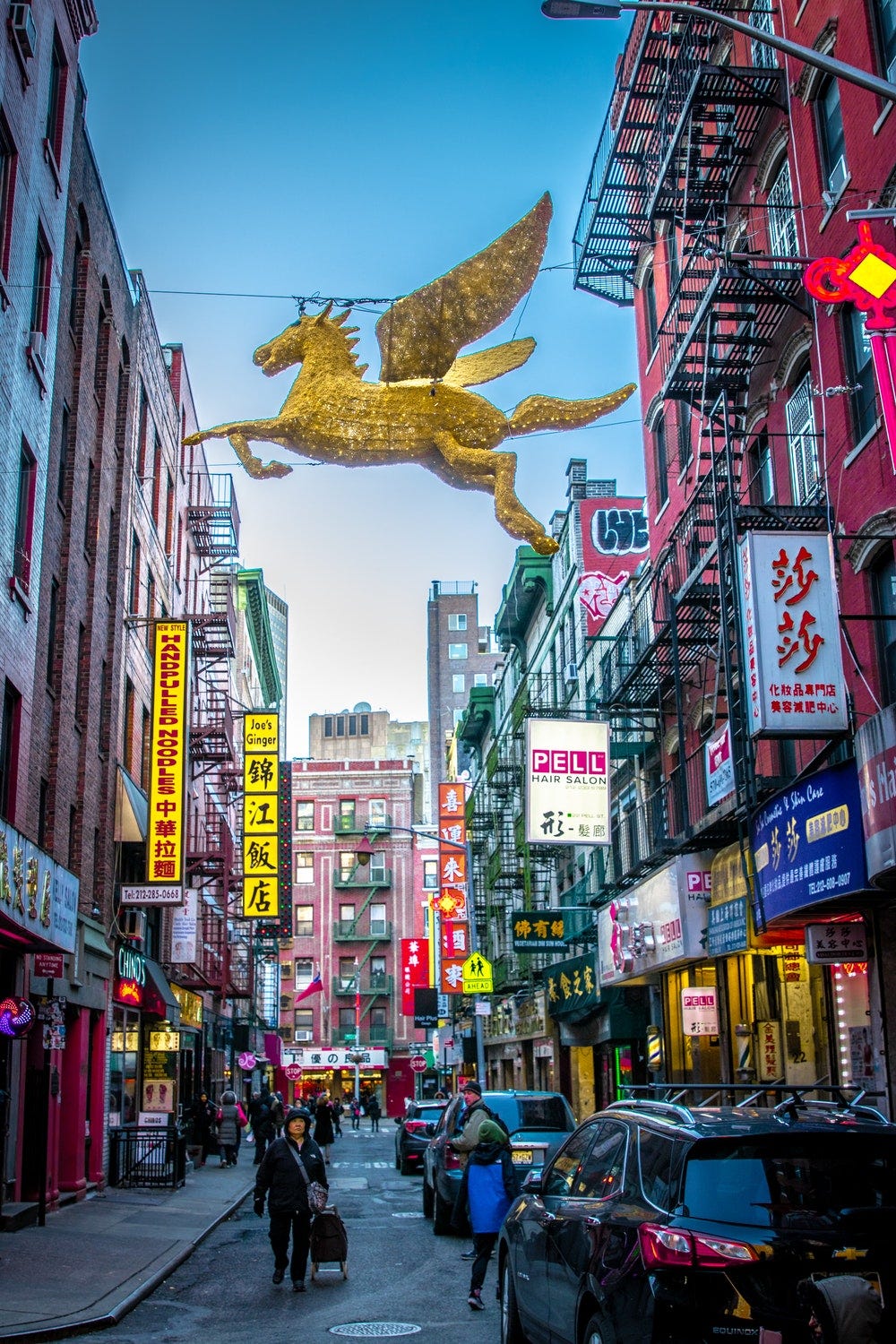 people walking under gold unicorn decor on street