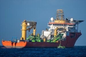 A view of the Normand Energy deploying the Patania II nodule collector visible (green), seen from the Rainbow Warrior. The vessel is chartered by Global Sea Mineral Resources (GSR), a Belgian company researching deep sea mining in the Pacific. The company is currently testing mining gear with the aim of future commercial extraction of minerals from the seabed.