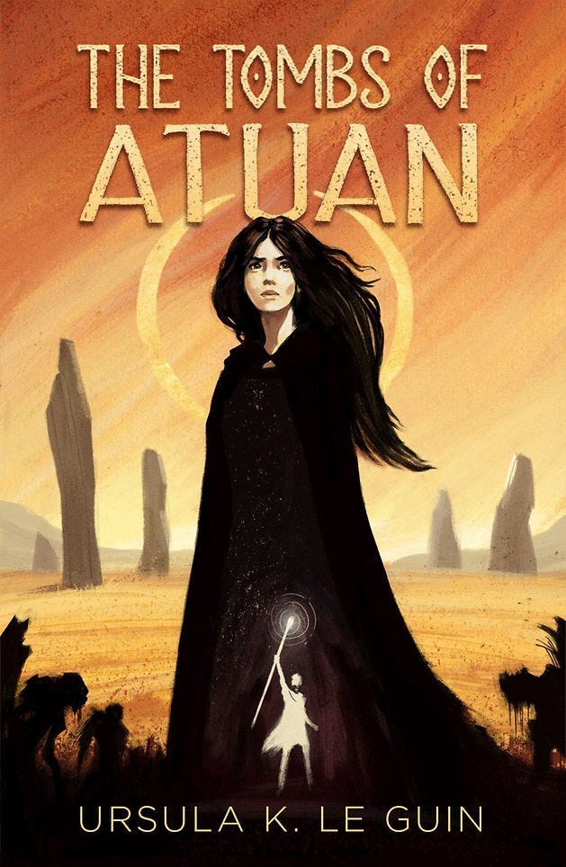 A woman in a dark cloak stands before monoliths on an orange desert. Text reads “The Tombs of Atuan” and “Ursula K. Le Guin”. A glowing figure holds a staff. A woman in a dark cloak stands before monoliths on an orange desert. Text reads “The Tombs of Atuan” and “Ursula K. Le Guin”. A glowing figure holds a staff.