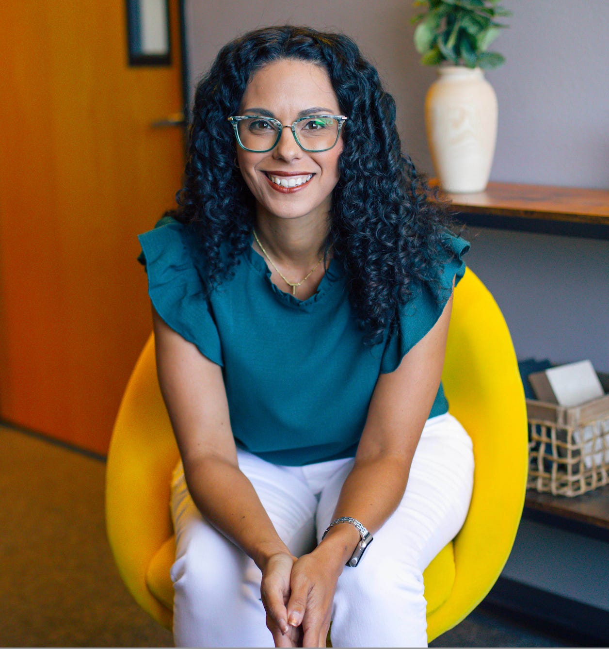 Torrie Sorge - Writer, Speaker, Editor, Consultant. Hispanic woman with teal shirt, white jeans, glasses and curly black hair sitting in a yellow chair in an office. Torrie Sorge - Writer, Speaker, Editor, Consultant. Hispanic woman with teal shirt, white jeans, glasses and curly black hair sitting in a yellow chair in an office.