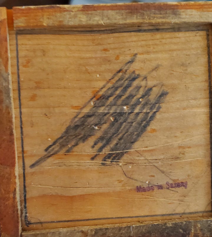 A small wooden box with triangular puzzle pieces inside, and a scribble of pencil outside.