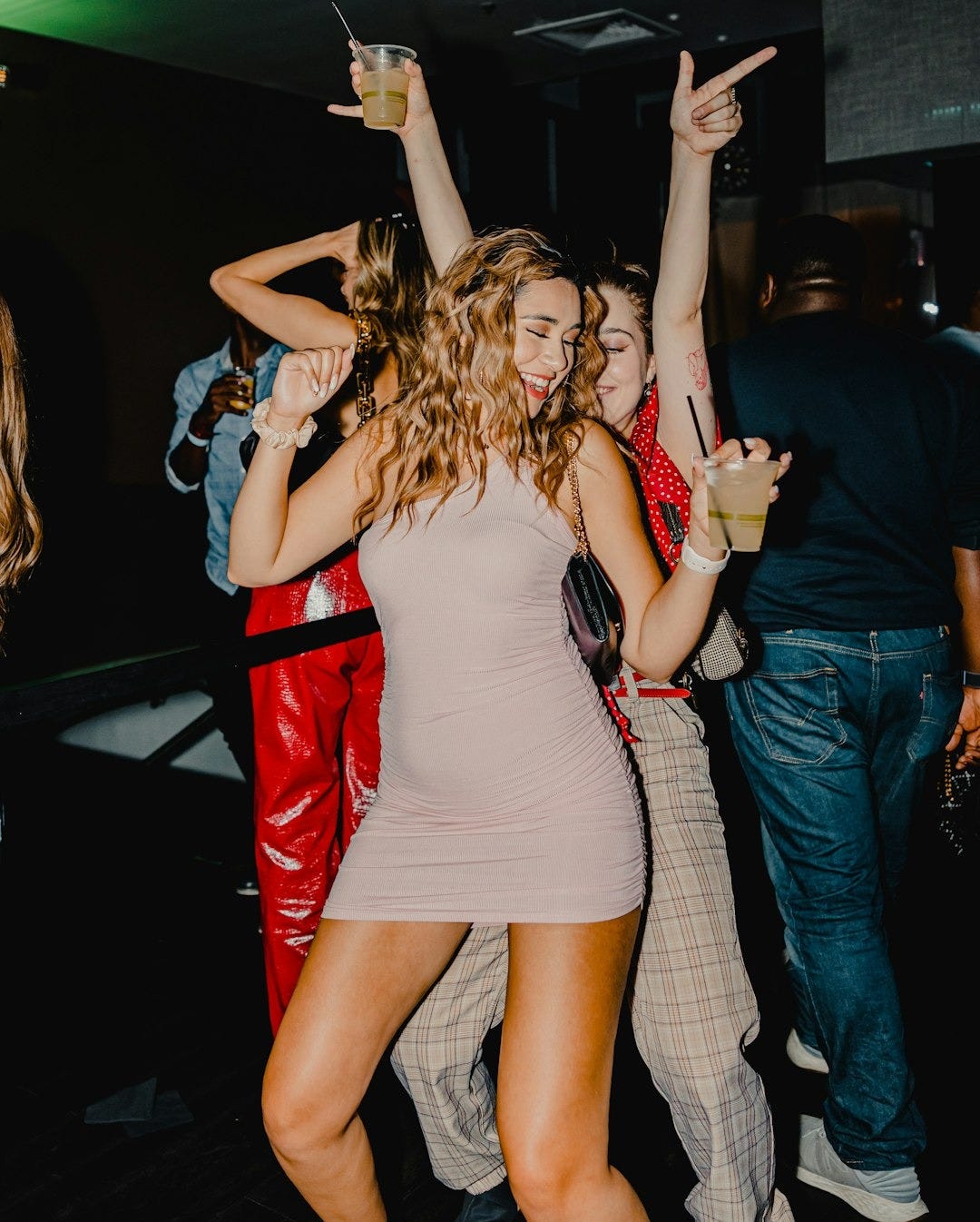 woman in red tank top and blue denim shorts standing beside woman in black tank top woman in red tank top and blue denim shorts standing beside woman in black tank top