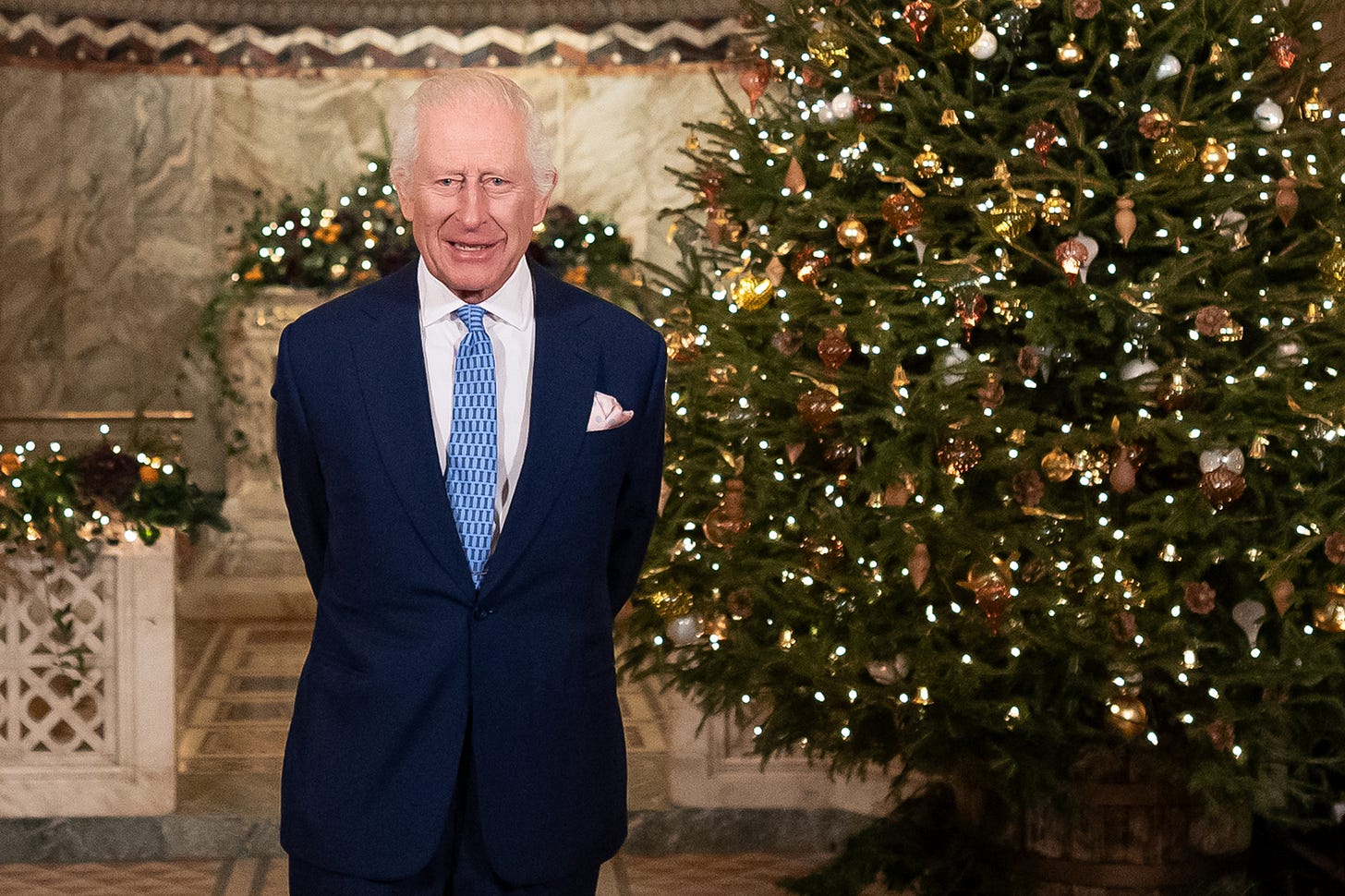 King Charles in front of a Christmas tree